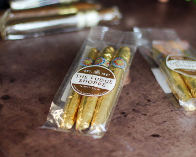 Packaged gold fudge cigars from The Fudge Shoppe on a textured surface