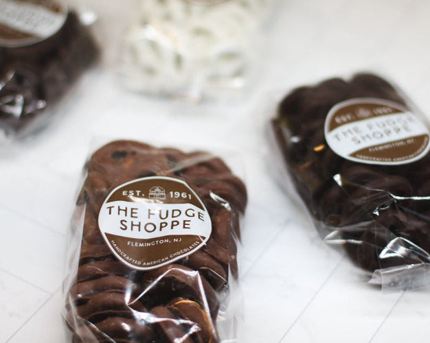 Packages of chocolate mini pretzels from The Fudge Shoppe on a white surface