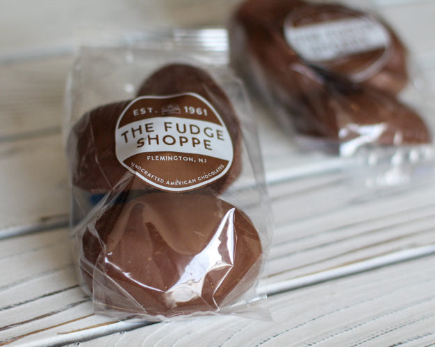 cookies n cream marshmallow eggs in clear packaging with 'The Fudge Shoppe' label on a wooden surface.
