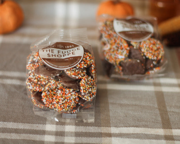 Chocolate Non pareils with fall sprinkles on a plaid tablecloth.
