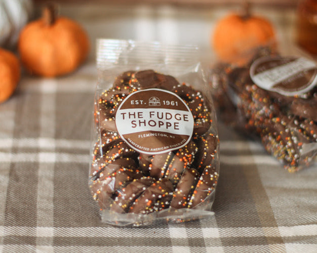 Packaged sprinkle pretzels on a plaid tablecloth with pumpkins in the background.