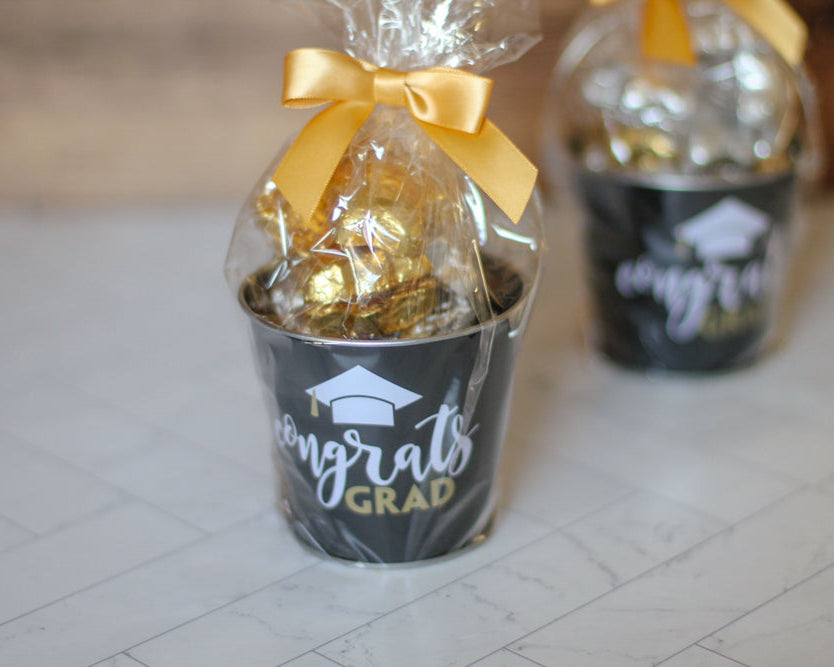 Graduation-themed gift with gold candy and 'Congrats Grad' text on a white surface.
