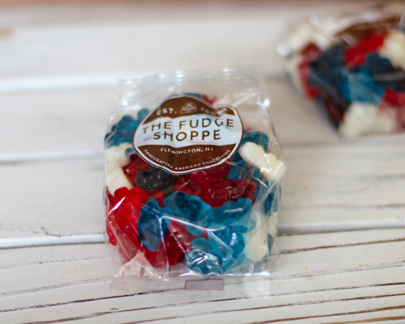 Packaged red, white, and blue gummy bears with 'The Fudge Shoppe' label on a wooden surface.