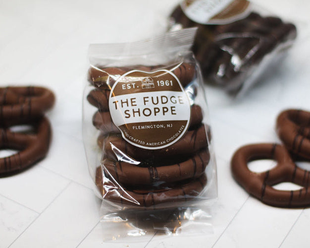 Packaged chocolate pretzels from The Fudge Shoppe on a white surface