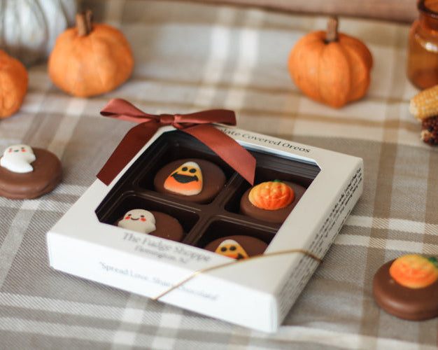 Box of Halloween themed oreos on a plaid tablecloth with pumpkins and cornbread.