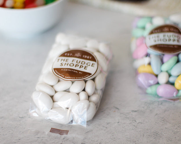 Packaged Jordan Almonds in white and pastel colors displayed on a counter.
