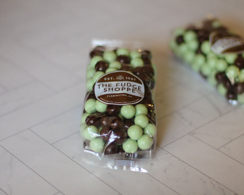 Two packages of The Fudge Shoppe chocolate-covered candies on a tiled floor.