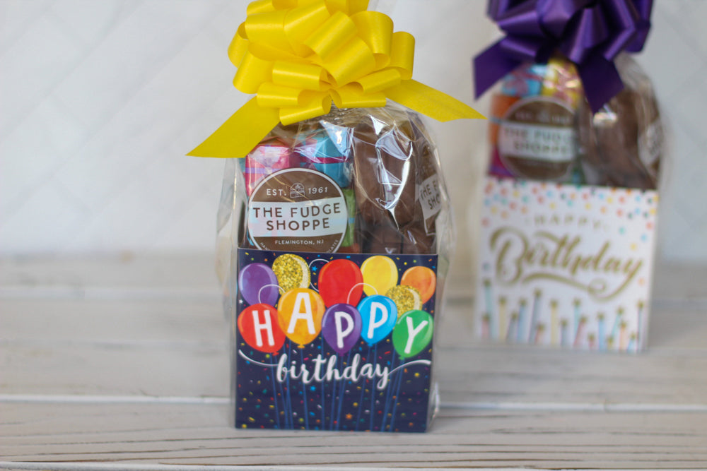 Two gift bags with chocolates and decorative ribbons on a wooden surface.