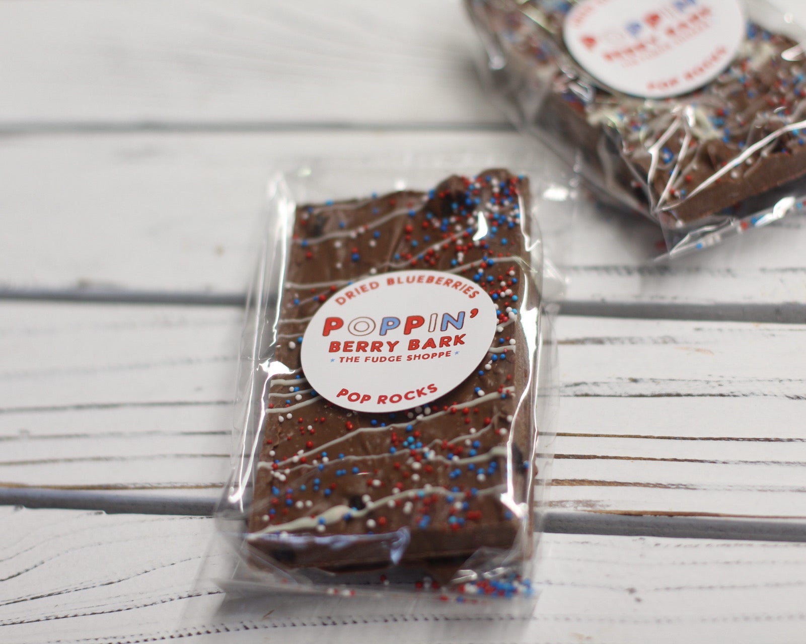 Poppin' Berry Bark on a stick with packaging on a wooden surface