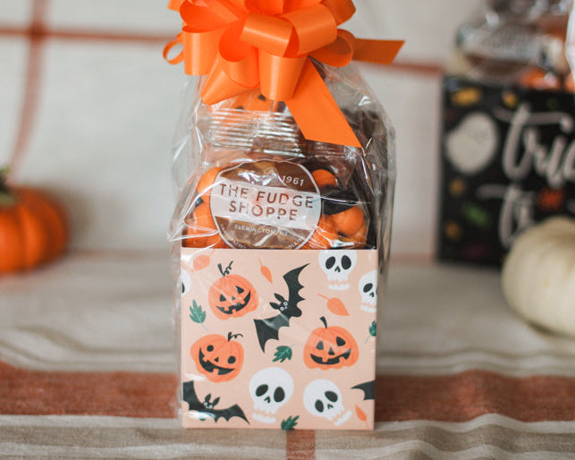 Halloween-themed candy bag with orange bow and 'The Fudge Shoppe' label, surrounded by pumpkins and a 'Trick or Treat' sign.