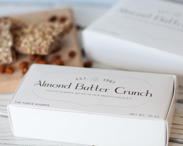 Box of Almond Butter Crunch fudge on a wooden surface with a blurred background