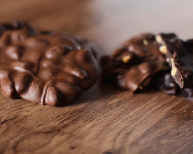 Chocolate nut bark made with dark chocolate and almonds, placed on a wooden surface.