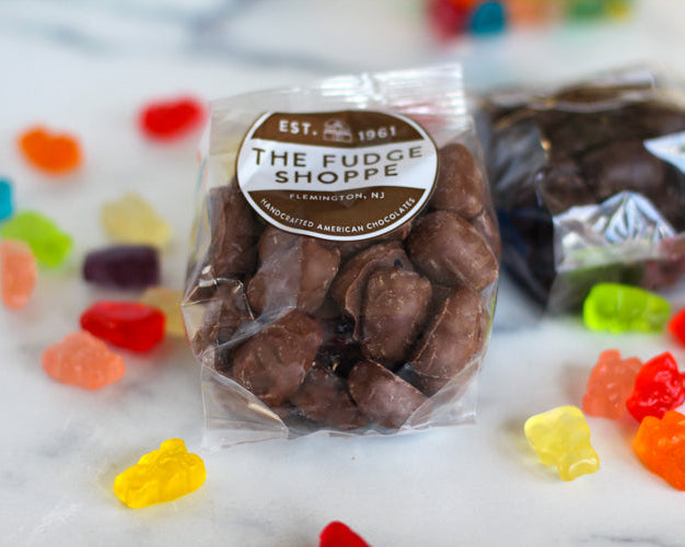Packaged chocolate gummi bears with on a marble surface with gummy bears around it.
