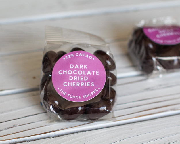 Packaged dark chocolate dried cherries with a pink label on a white background