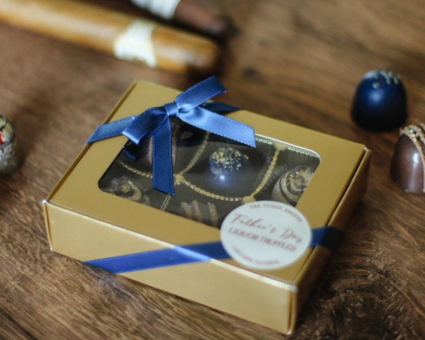  Gold box of liquor truffles with a blue ribbon on a wooden surface