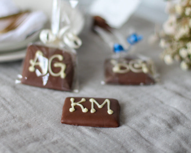 Chocolate bars with initials 'AG', 'BK', and 'KM' on a textured surface.