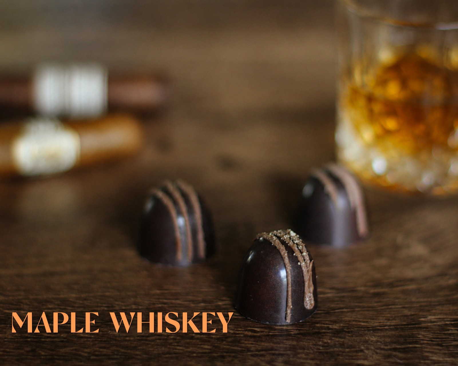 Chocolate truffles with a glass of maple whiskey on a wooden surface