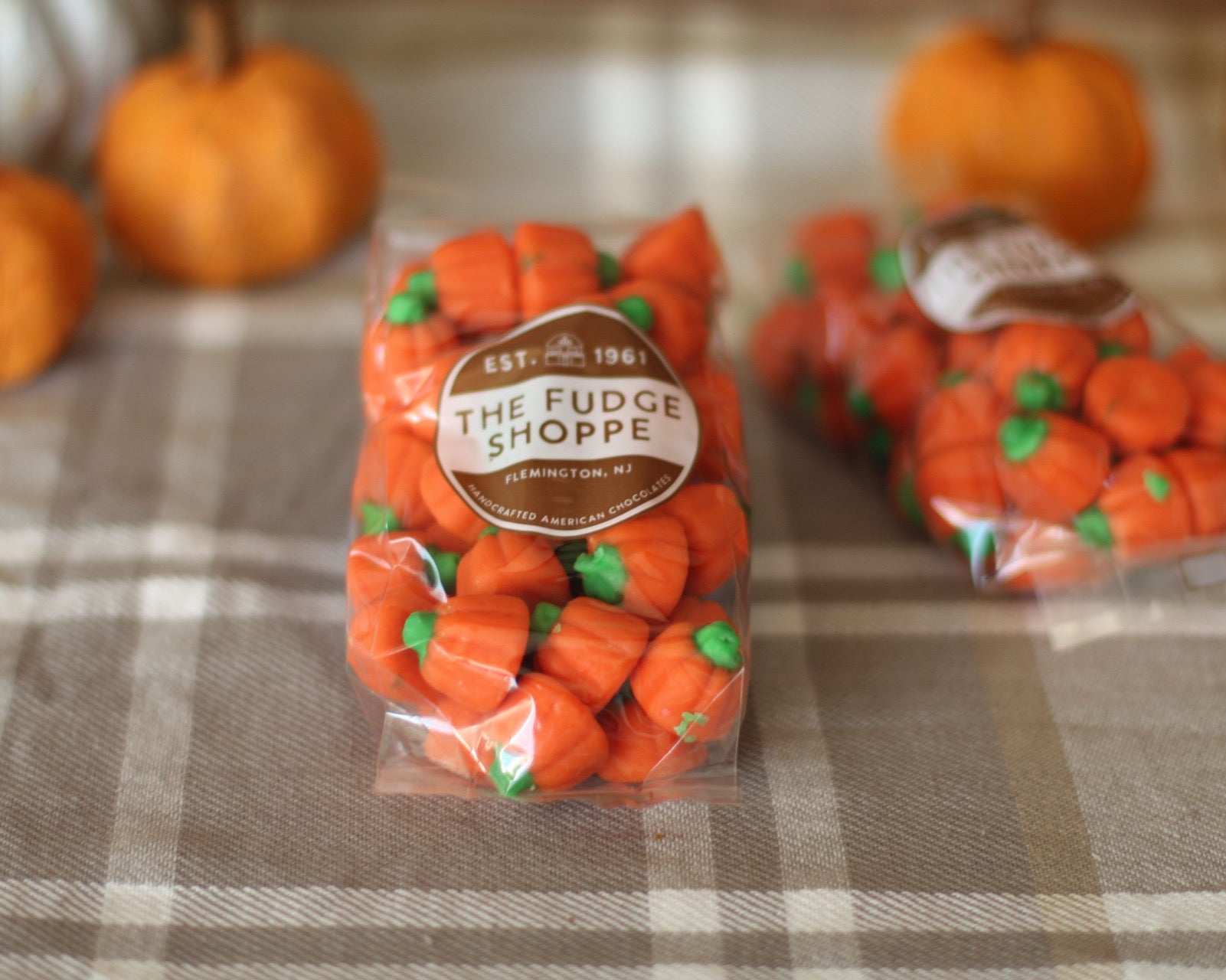 Mellowcreme pumpkins on a plaid surface with pumpkins in the background.