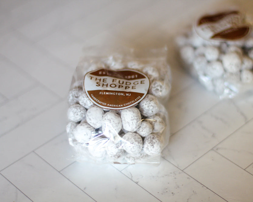 Two bags peanut snowballs with 'The Fudge Shoppe' label on a tiled floor.