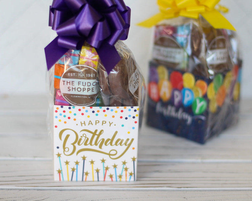 Gift basket with a 'Happy Birthday' card and a purple bow, with another gift basket in the background.