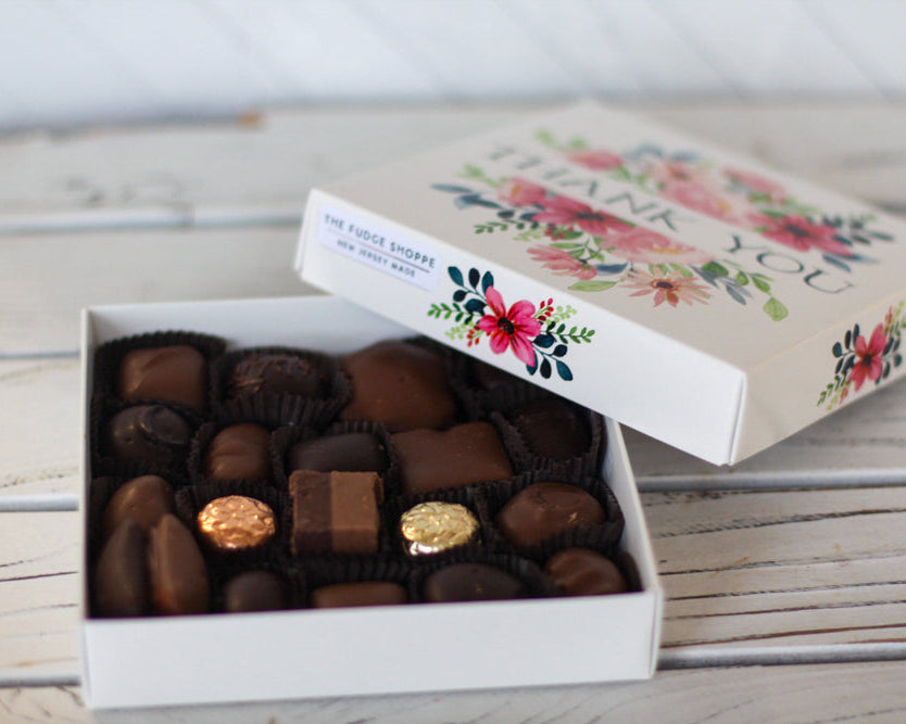 Box of chocolates with a 'thank you' card on a wooden surface