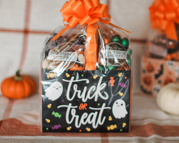 Gift bag with Halloween-themed design and orange bow on a checkered tablecloth.