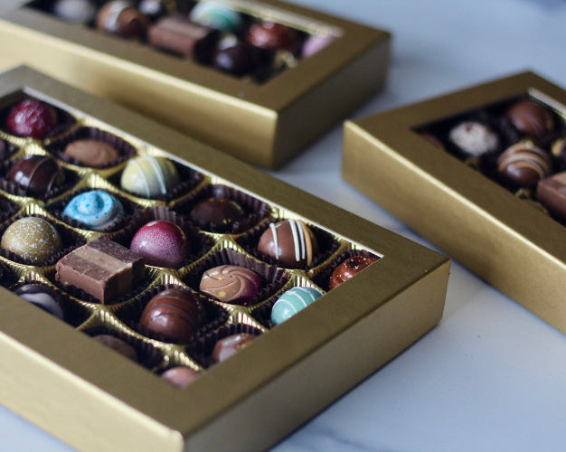 Boxes of assorted chocolate truffles with visible different flavors such as caramel, irish cream, and cherry.