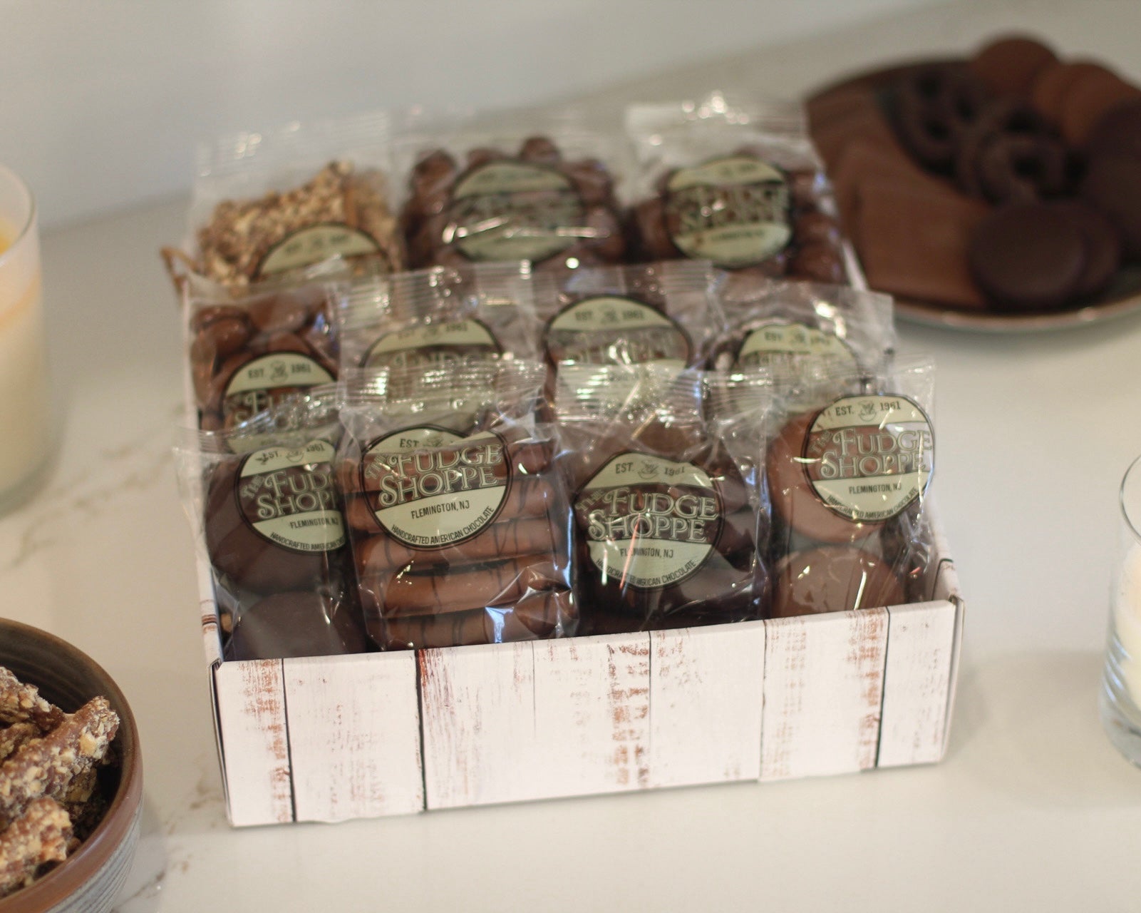 A gift basket containing an assortment of chocolates including almond butter crunch, oreos, malt balls, pretzels, graham crackers, nonpareils, raisins, caramel corn, and smores.
