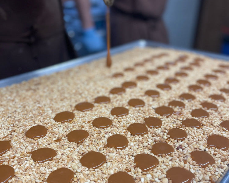 caramel being set onto rows of nuts